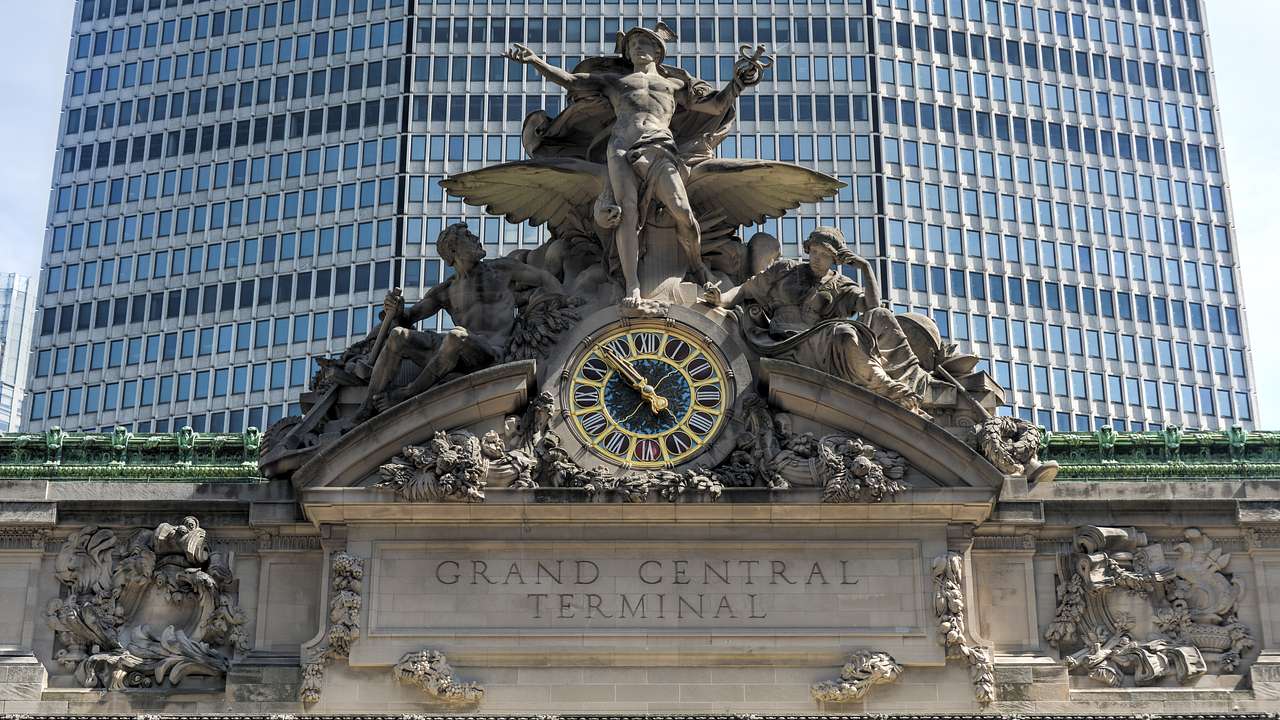 A stone Grand Central Terminal sign with clock and statue above it
