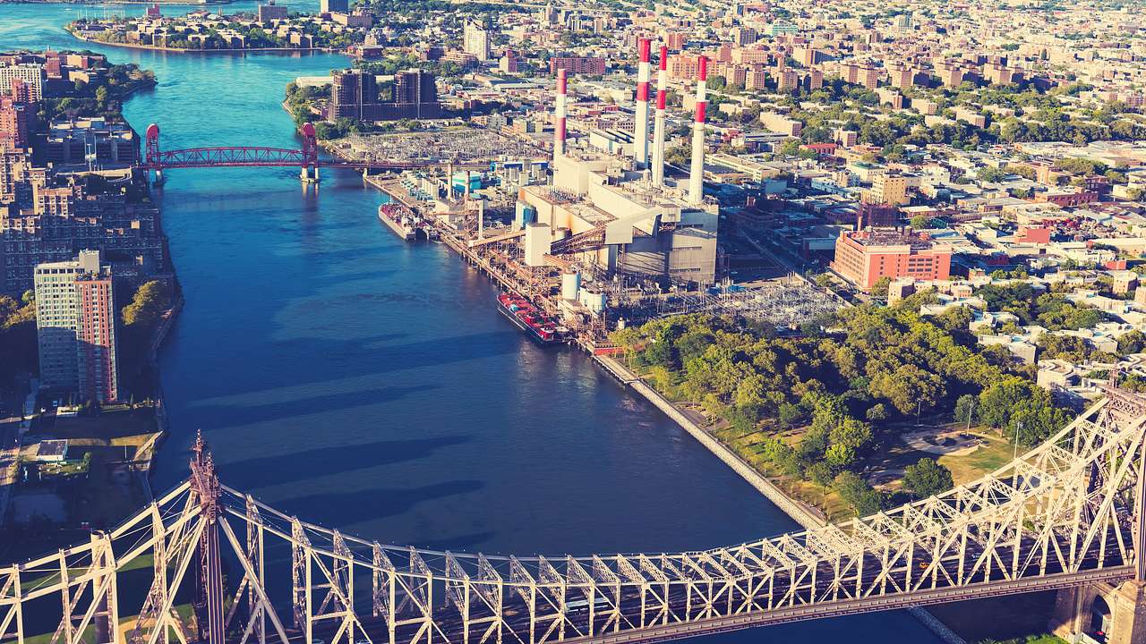Aerial view of a bridge, river, and city with a park and power generating station