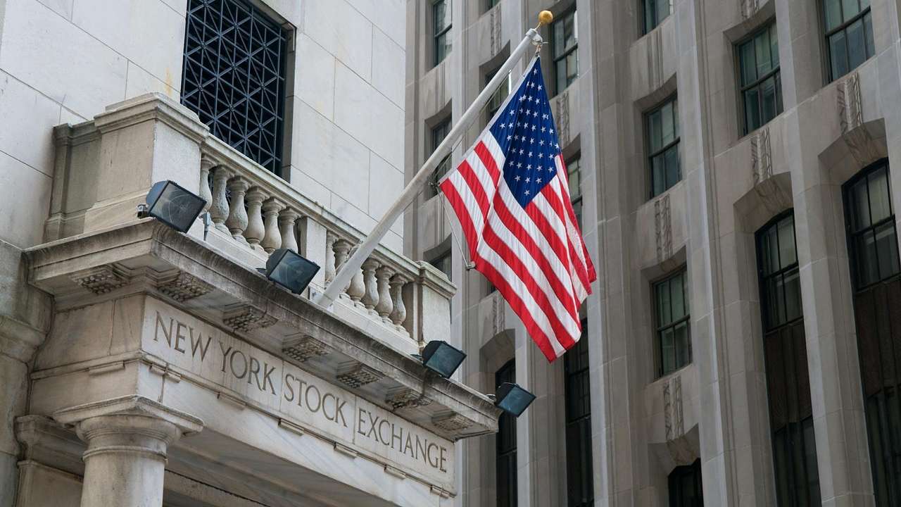 A stone building with New York Stock Exchange sign and an American flag