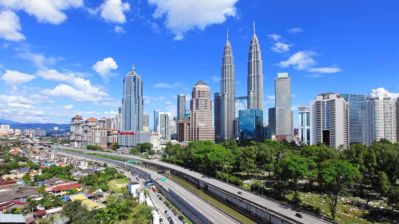A view of Kuala Lumpur with tall modern buildings, trees, and a highway