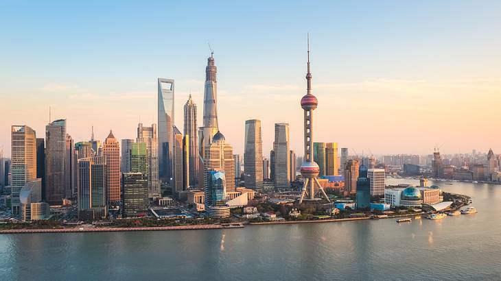 The Shanghai skyline with modern buildings next to water at sunset