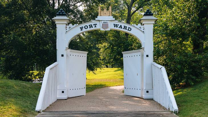 A white arched gate with a sign that says "Fort Ward" A white arched gate with a sign that says "Fort Ward"
