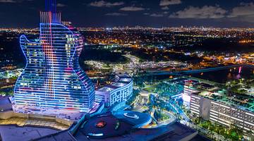 The Hard Rock Hotel at night with an illuminated guitar structure and pools