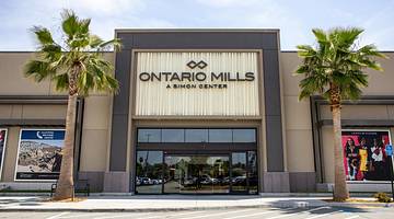 The exterior of a luxury shopping mall with an "Ontario Mills" sign and palm trees