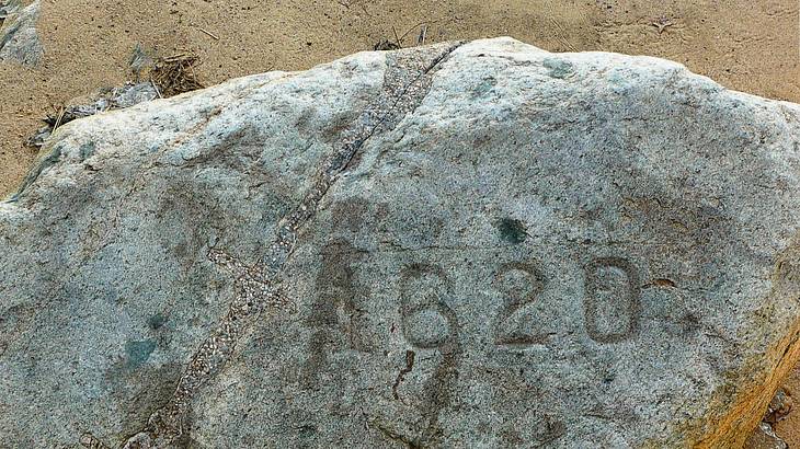A grey rock on the sand with the number 1620 engraved on it