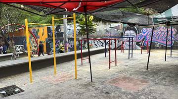 Metal gym bars and a playground under a red awning with graffiti at the back