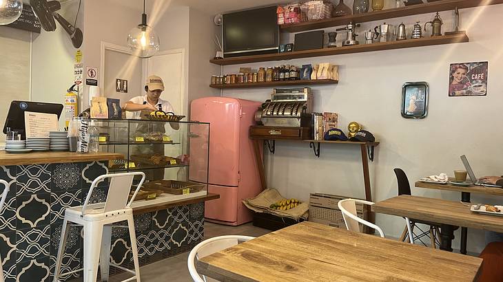 The inside of a cafe with tables on the right and a counter on the left