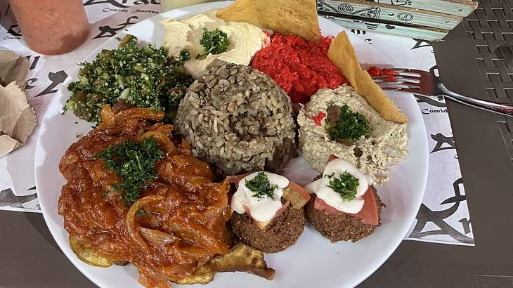 A platter of food including rice, dips, a salad and a tomato dish