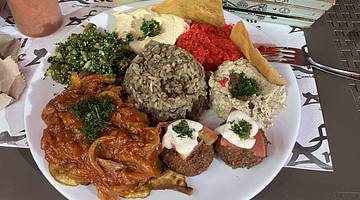 A platter of food including rice, dips, a salad and a tomato dish