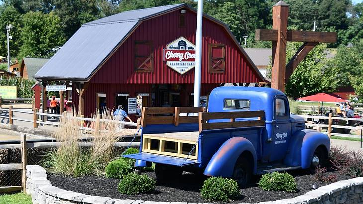 A blue model truck next to a red farm barn with a sign that says "Cherry Crest"