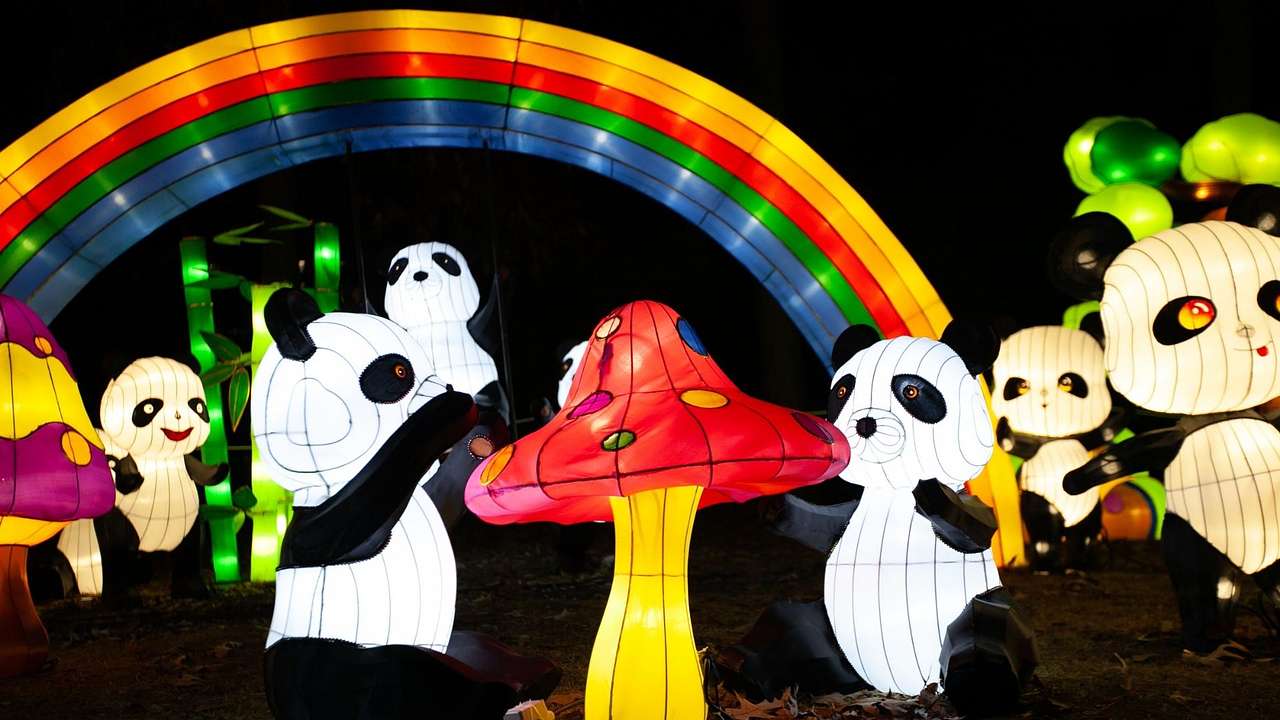 An illuminated lantern display with pandas, a red mushroom, and a rainbow