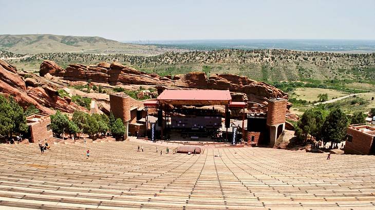 An outdoor theater surrounded by red rocks and greenery under a blue sky