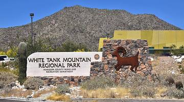 A hill behind a sign that says "White Tank Mountain Regional Park"
