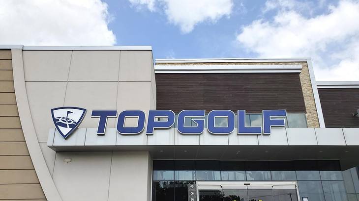 The exterior of a building with a blue Topgolf sign on it