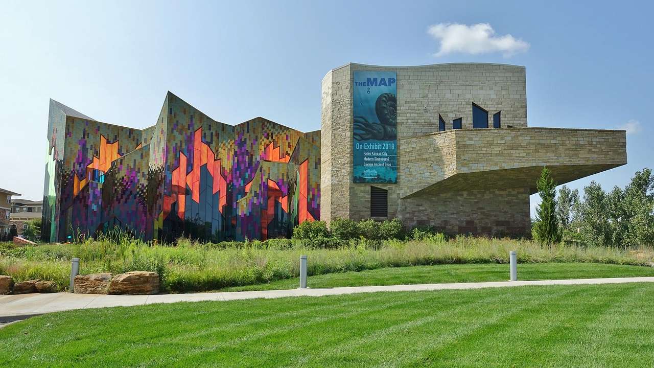A museum with colored glass next to a stone building with grass in front of it
