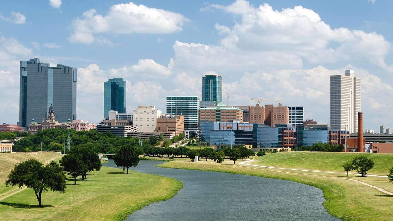 The Fort Worth city skyline next to a river, grass, and trees