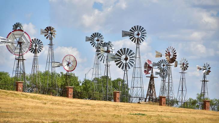 Multiple American windmills on the grass under a blue sky with clouds Multiple American windmills on the grass under a blue sky with clouds