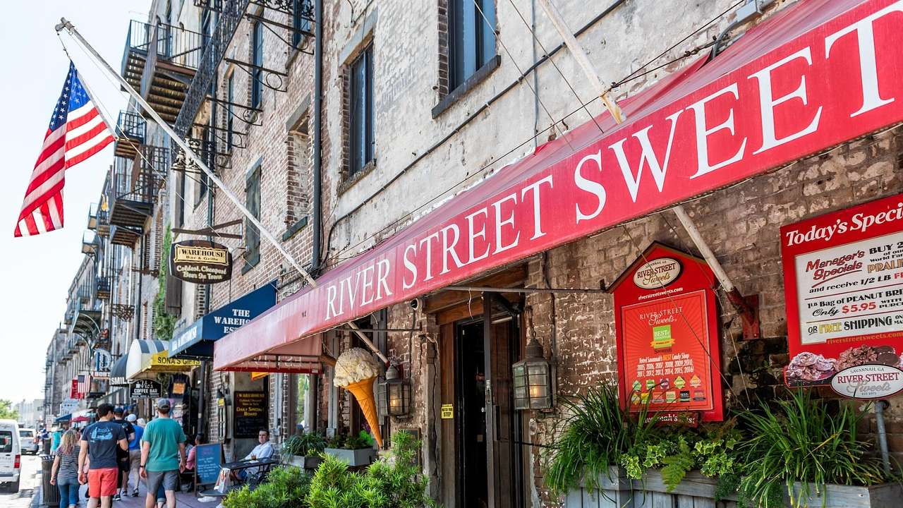 The exterior of a brick building with a red awning that says "River Street Sweet"
