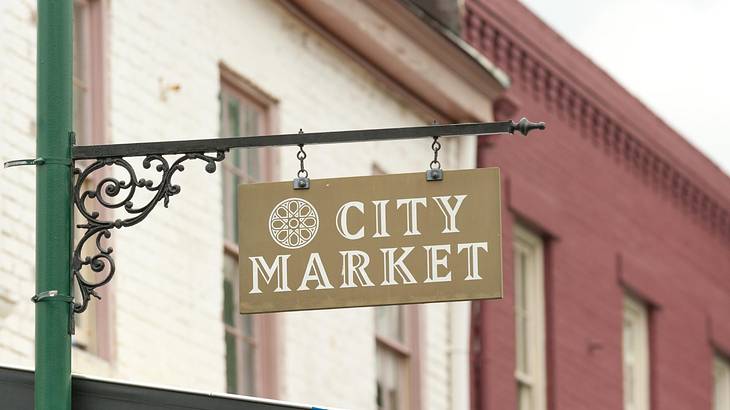 A sign that says "City Market" with brick buildings in the background