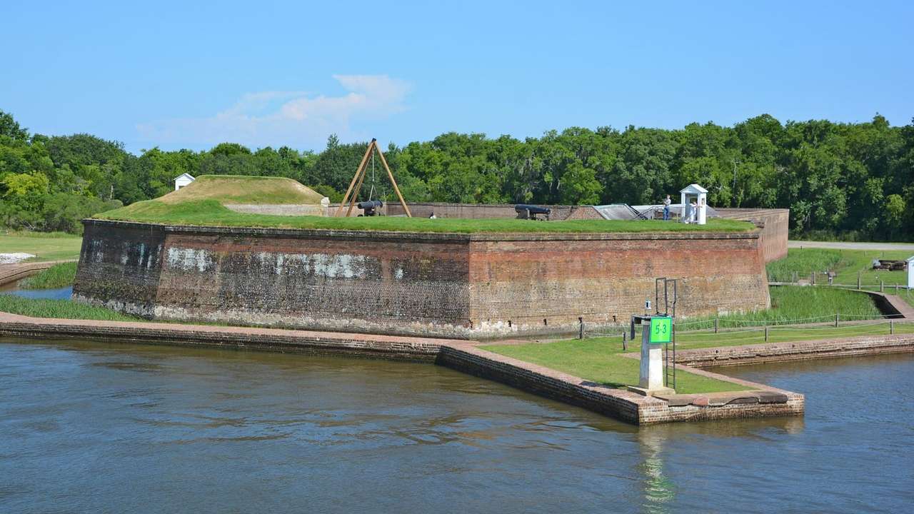 An old fort structure with grass around it next to the water