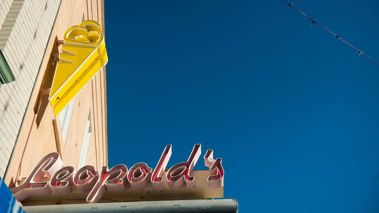 A sign that says "Leopold's" below a yellow ice cream cone sign next to a blue sky