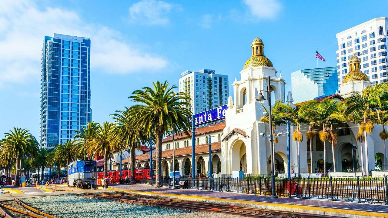 A railway track next to palm trees and a white stone building with a gold dome
