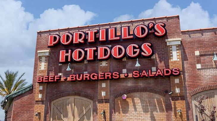 A brick building with a red sign that says "Portillo's Hotdogs"