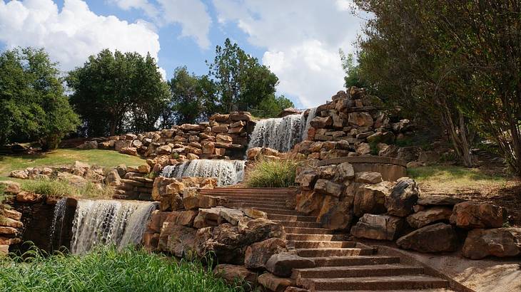 Small waterfalls next to some steps and surrounded by greenery