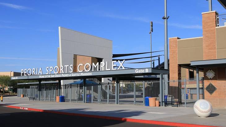The entrance to a stadium with a sign that says "Peoria Sports Complex"
