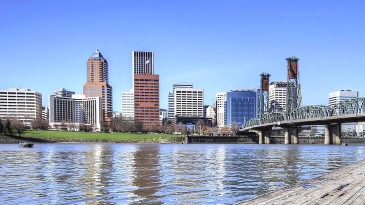 City buildings next to a bridge and a river under a clear blue sky