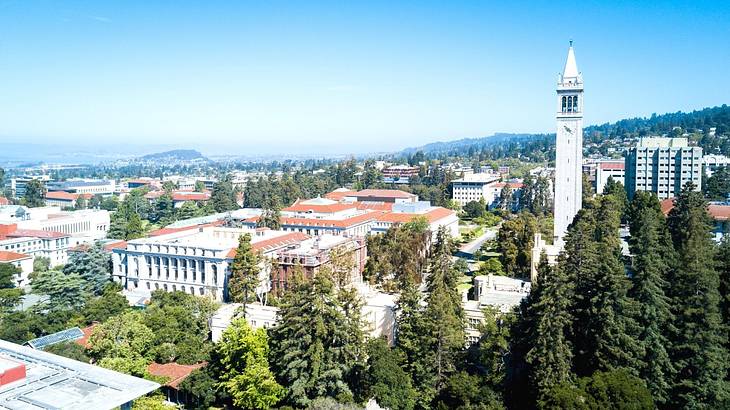 A view over a town with trees, white buildings, and a white tower