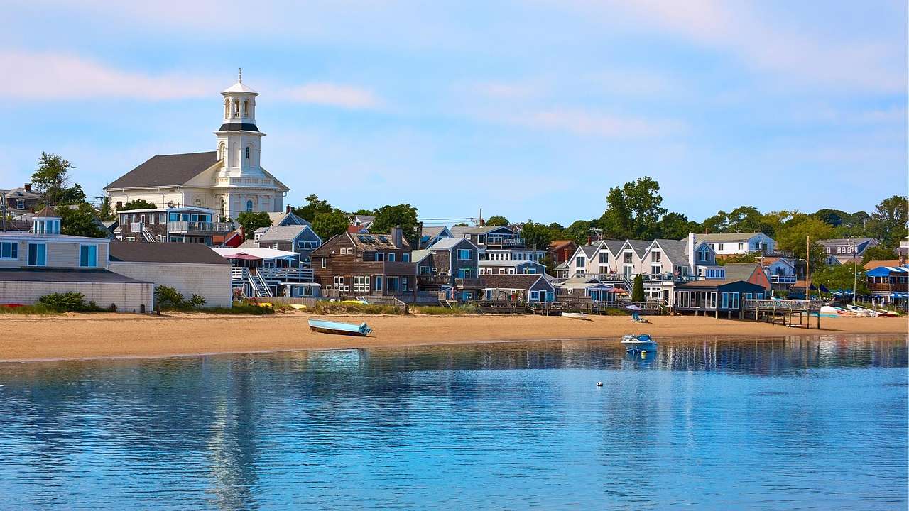 A beach next to a New England town with small houses and a white church