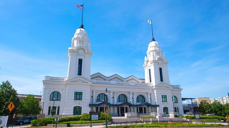 A white station building with two towers next to trees under a clear blue sky