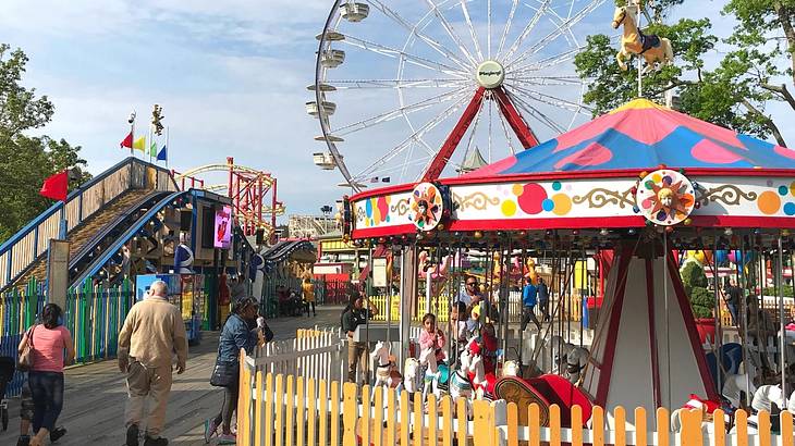 A small theme park with a colorful carousel, Ferris wheel, and slide