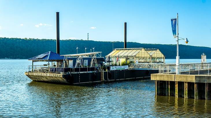 A barge on the river with a small greenhouse onboard