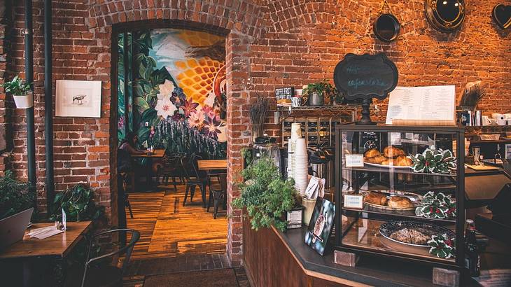 The interior of a coffee shop with a brick wall and a display of baked goods