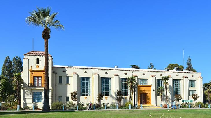 A white building with orange details next to green grass and a palm tree