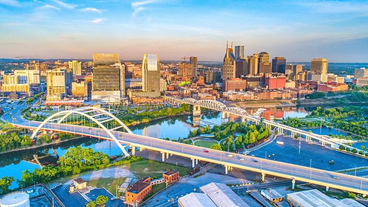 An aerial view of a city with bridges over a river, trees, and buildings at sunset