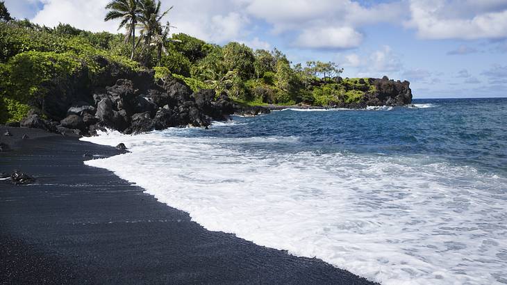 Ocean waves washing up along a black sandy beach