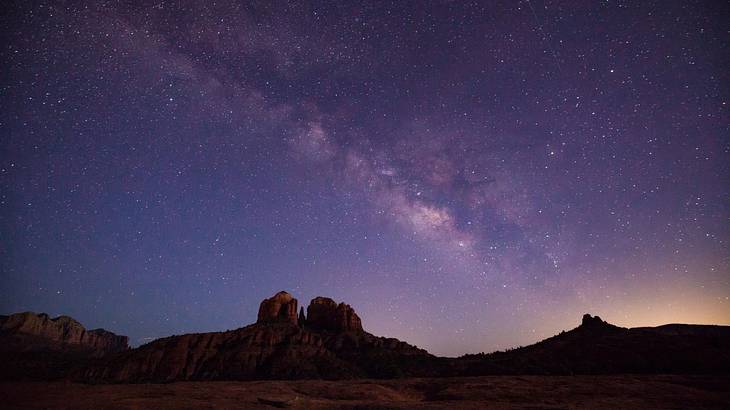 Rocky hills in the desert at night under a purple sky with stars Rocky hills in the desert at night under a purple sky with stars