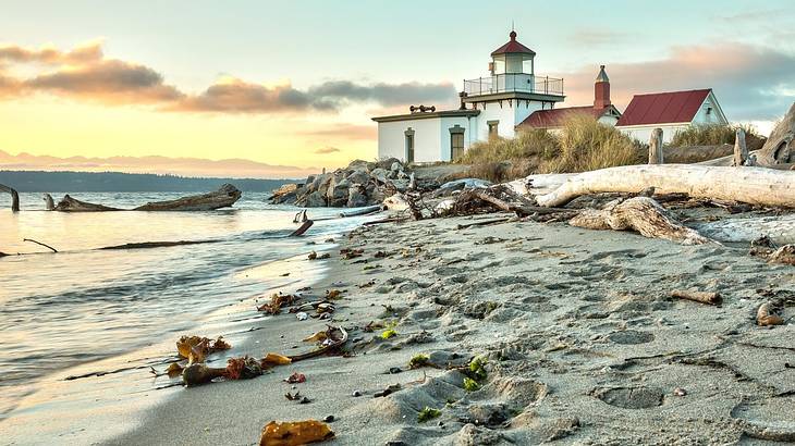 A white and red lighthouse building next to a sandy shore and the ocean at sunset A white and red lighthouse building next to a sandy shore and the ocean at sunset