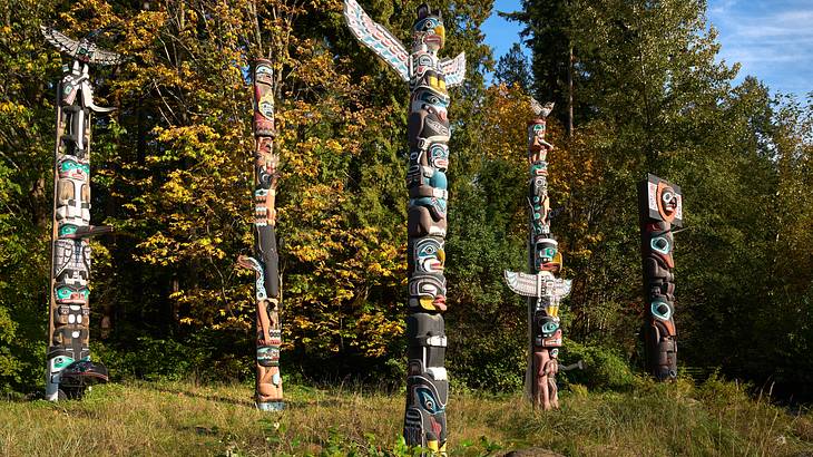 Tall Indigenous totem poles amongst greenery
