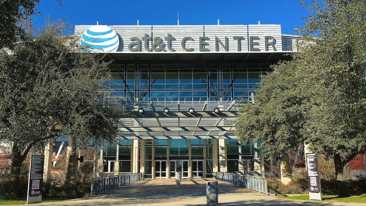 A sports arena that says AT&T Center with a path and trees in front of it