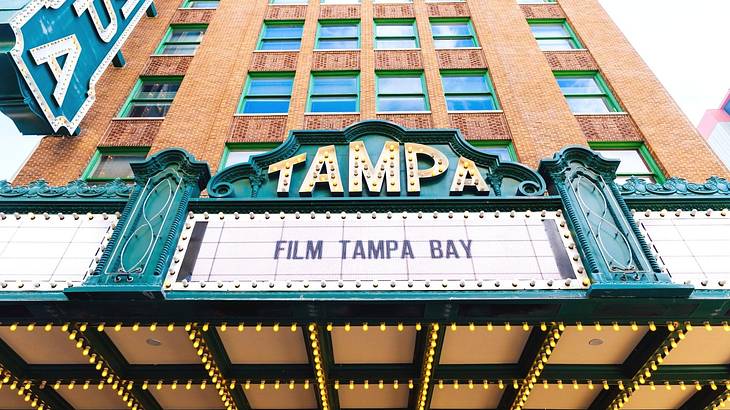A sign on a red brick building that says "Tampa" with "Film Tampa Bay" underneath it