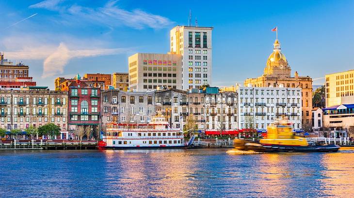 Water with boats docked on it and city buildings on the shore on a clear day