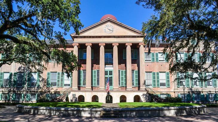 A building with columns and trees and grass in front of it