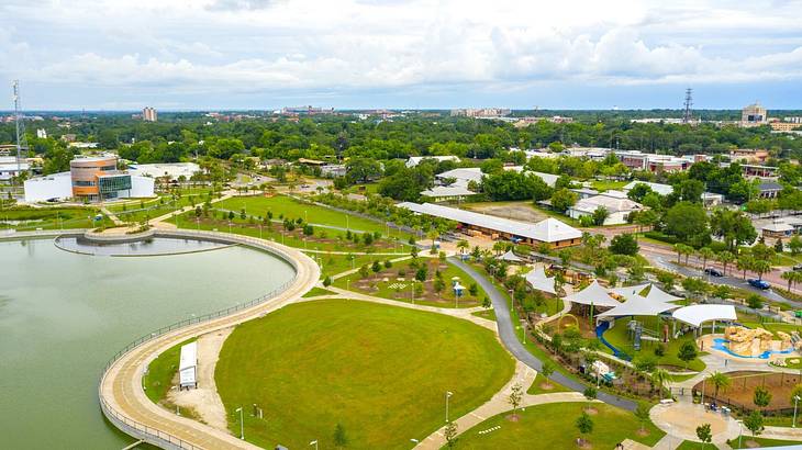 An urban park with green grass and trees next to a lake