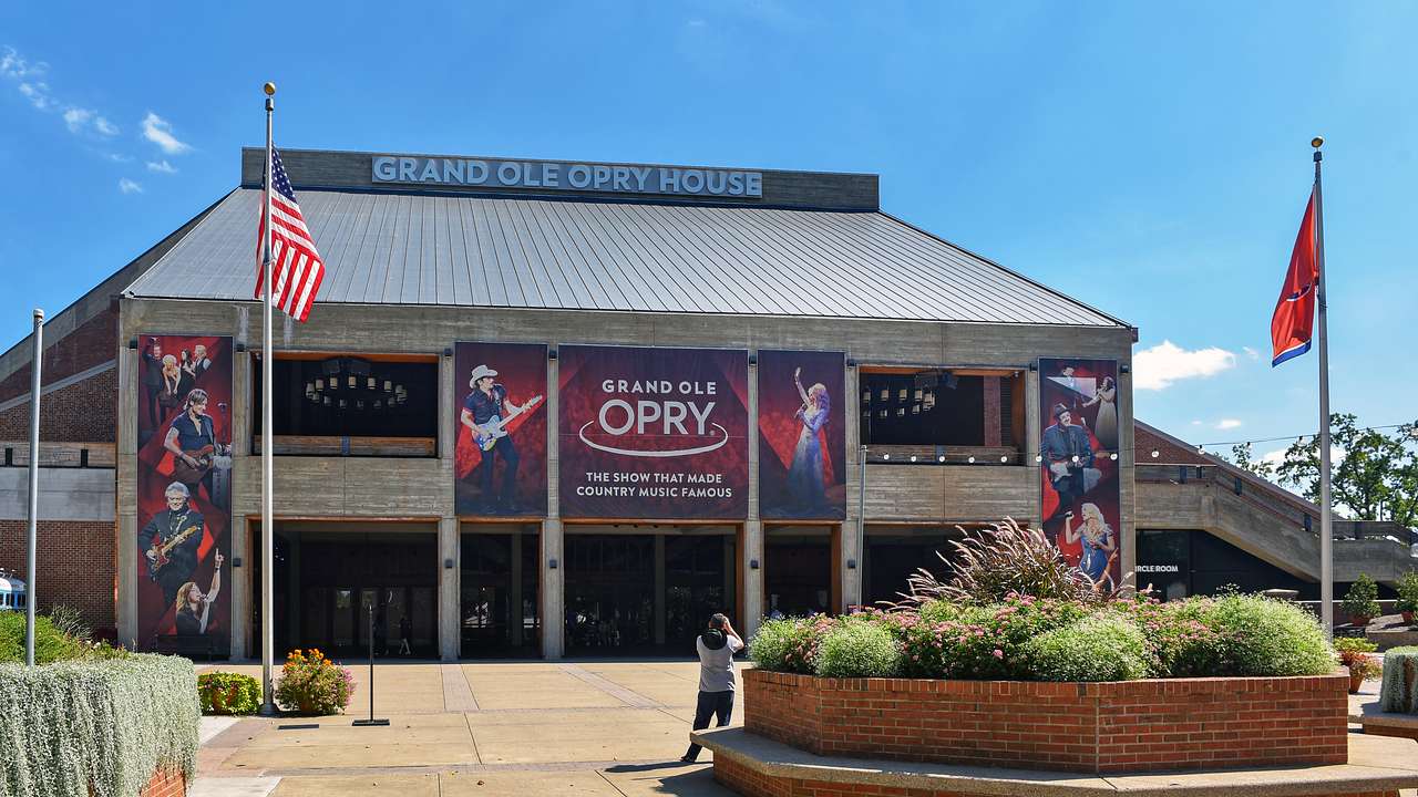 A music hall with a Grand Ole Opry banner and flags and a path in front of it