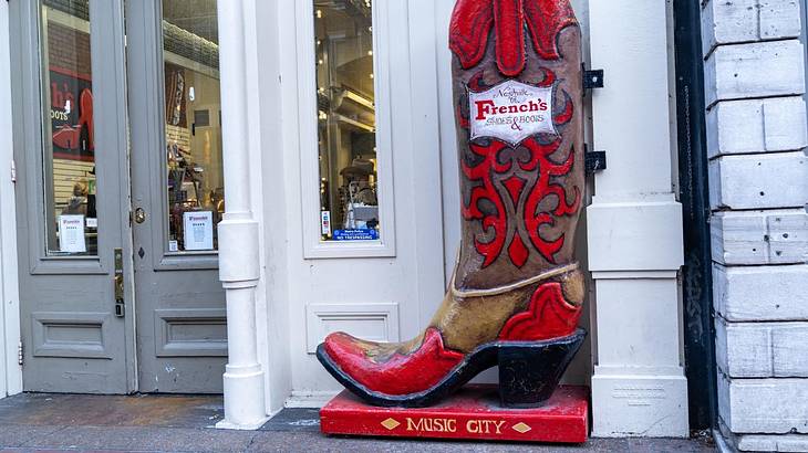 A cowboy boot sculpture outside a store with a "Music City" sign
