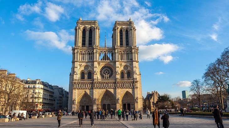 The Notre Dame Cathedral sitting in a square with people in front of it